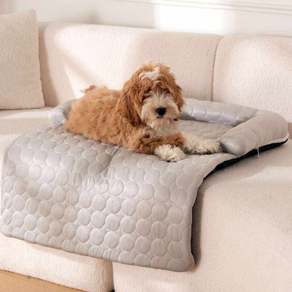 Bed Pet Cooling Mat in light gray quilted fabric with raised cushioned edges, shown supporting a small brown-and-white dog