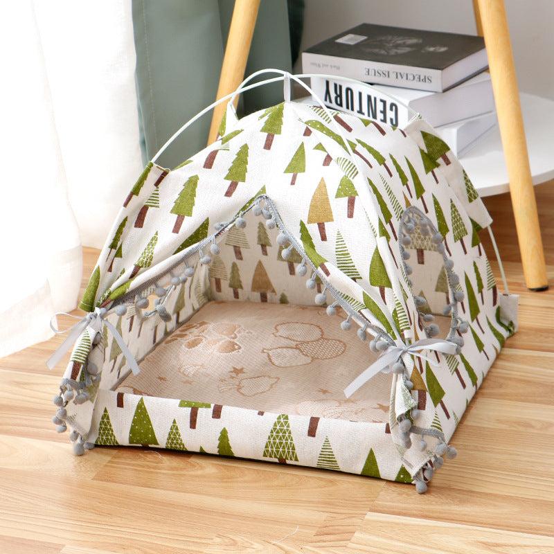 Enclosed Pet Bed in cream fabric with green and brown tree print, open tent-style cover and pom-pom trim