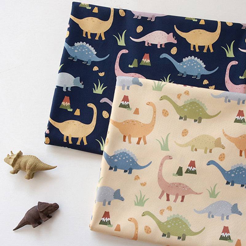 Handmade Printed Fabric in navy blue and cream cotton, patterned with colorful cartoon dinosaurs and tiny plants