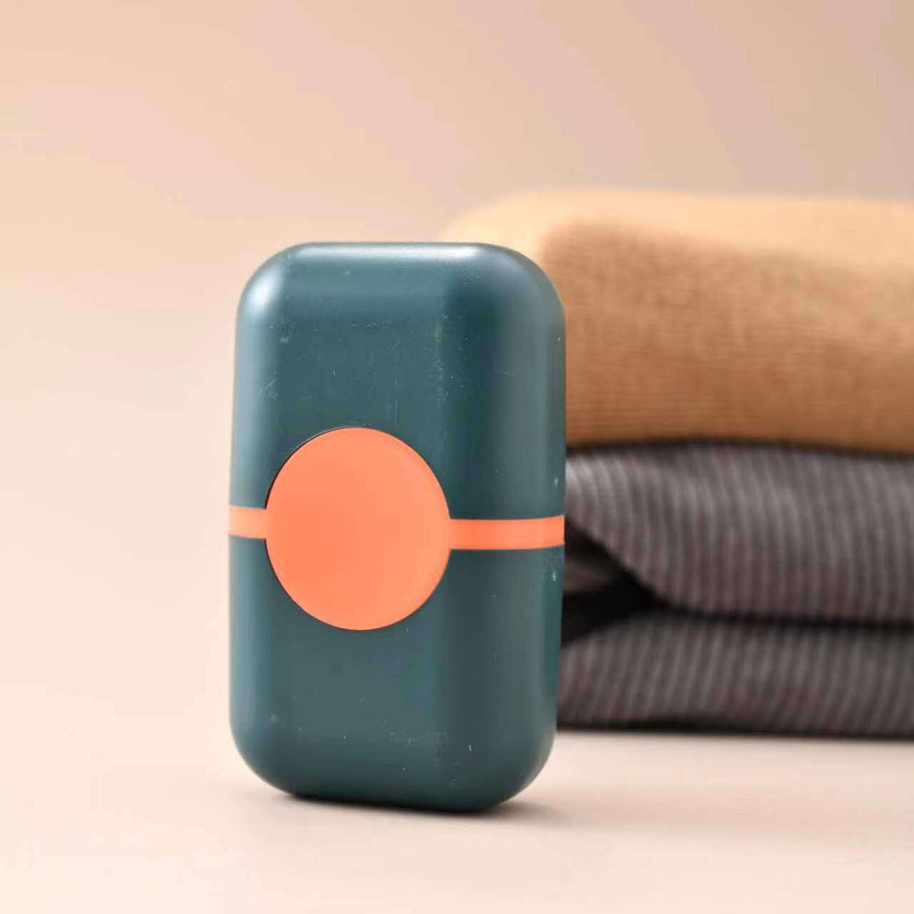 Pet Hair Double Headed lint roller in dark teal plastic with a coral orange circular accent and matching horizontal band