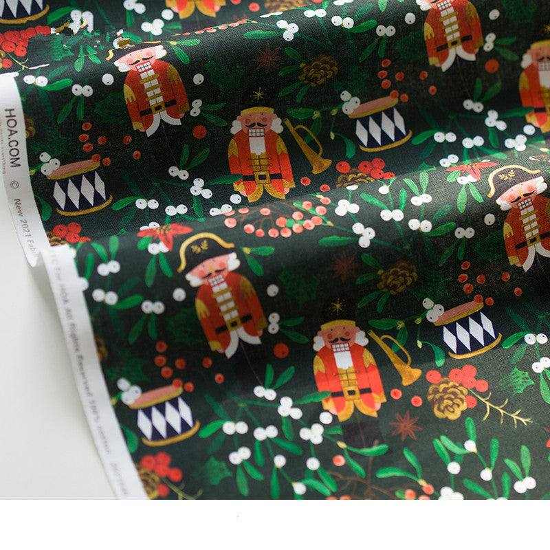 Printed Nutcracker Fabric in dark green cotton with colorful nutcracker soldiers, drums, holly, berries and pinecones
